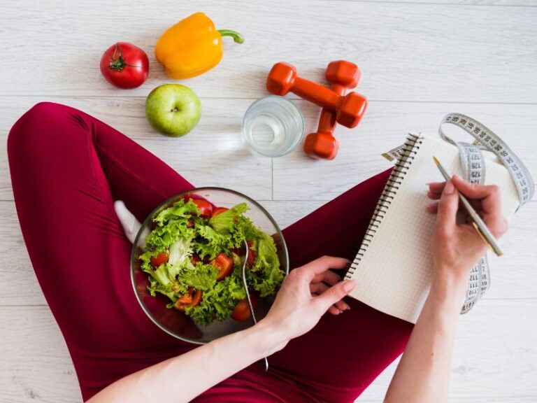 Person writing in notebook with healthy salad.