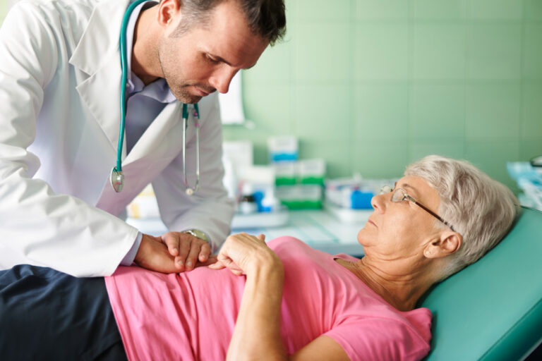 Doctor examining elderly patient lying on bed.