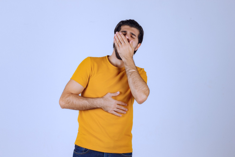 Man in yellow shirt holding stomach.