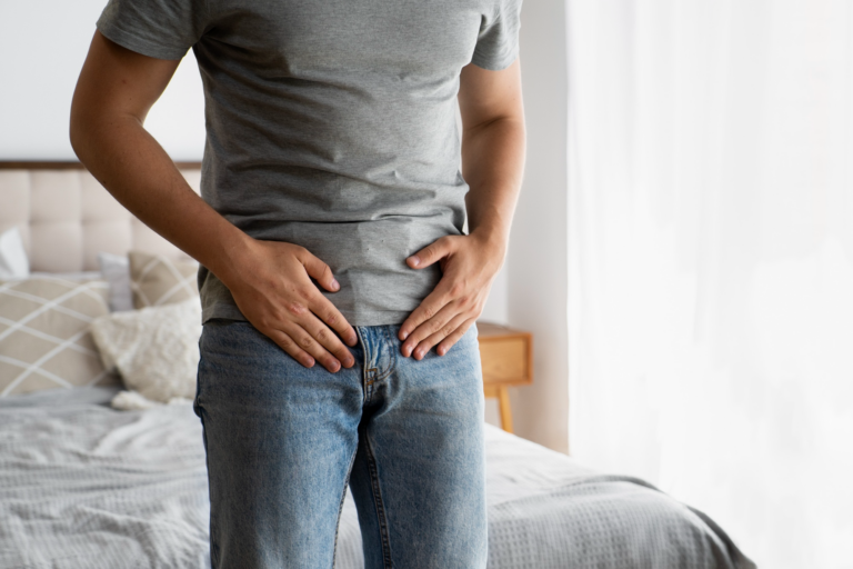 Man in gray shirt holding lower abdomen.