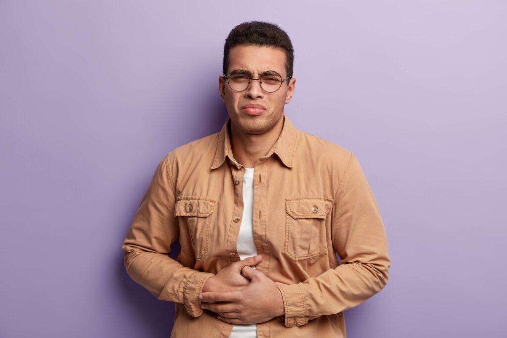 Man with stomach pain holding his abdomen.